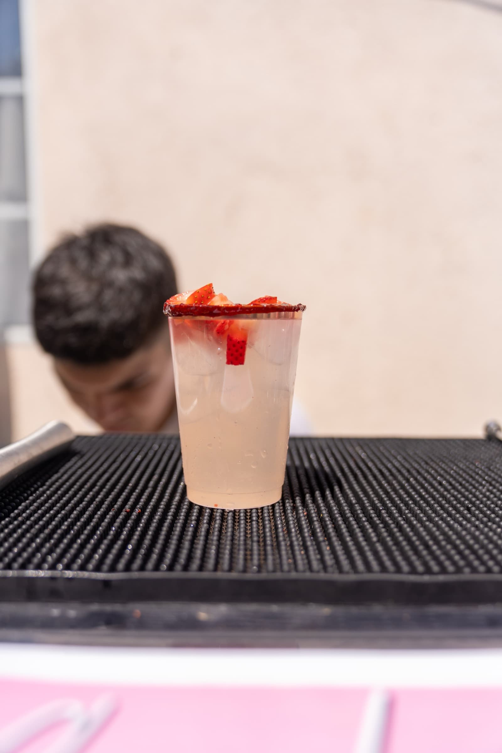 Strawberry chamoy michelada with bartender in the background